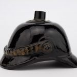 Antique black glass bottle in a shape of fireman helmet